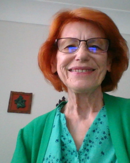 red hair woman with glasses smiles and wears a green top