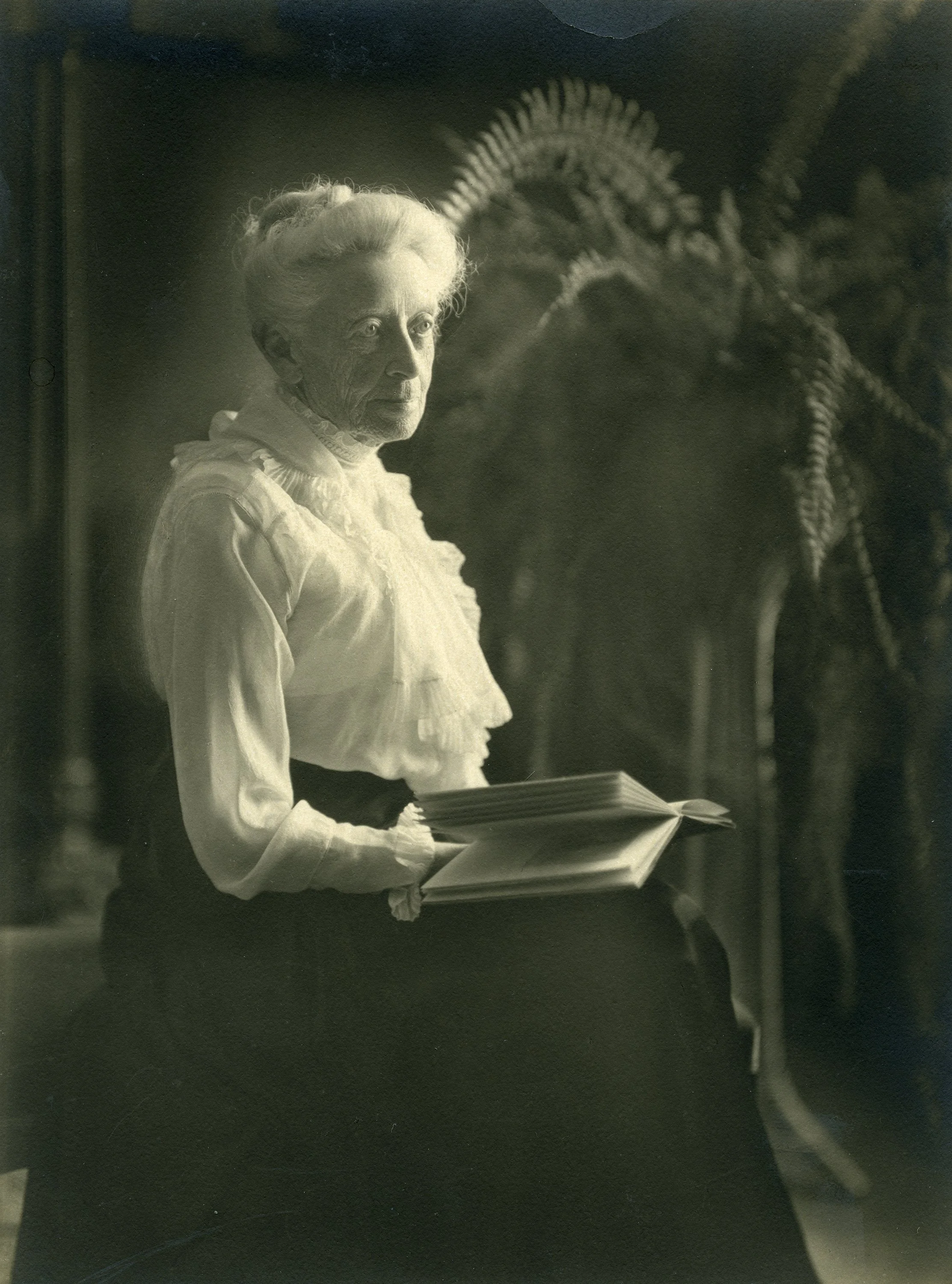 A black and white image of philanthropist Ellen Browning Scripps seated and with an open book on her lap.