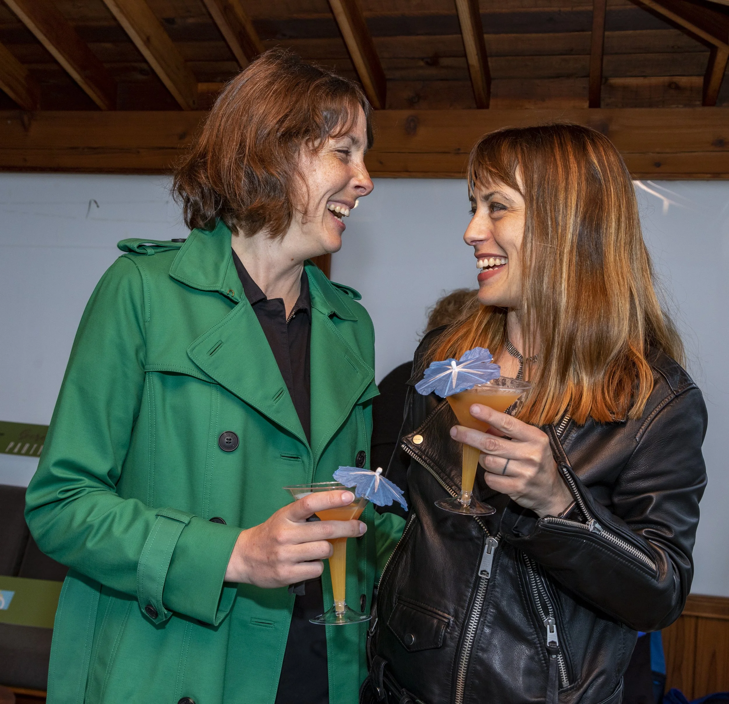 Two young women face each other while smiling and laughing.