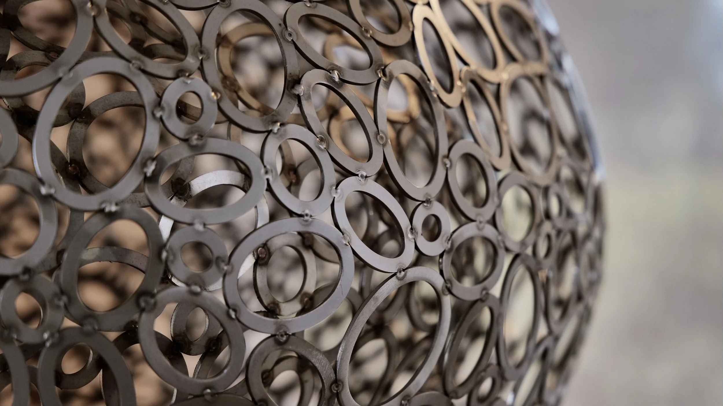 A close up detail of a metal artwork by Christopher Puzio consisting of metal rings.