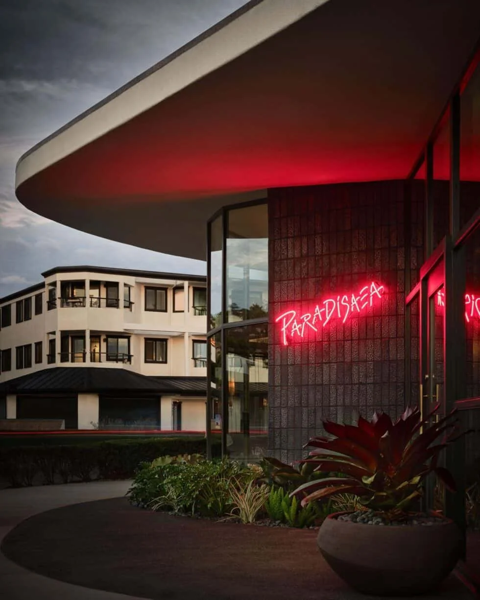 corner, curved business with windows all along the front with a neon sign on the brick details
