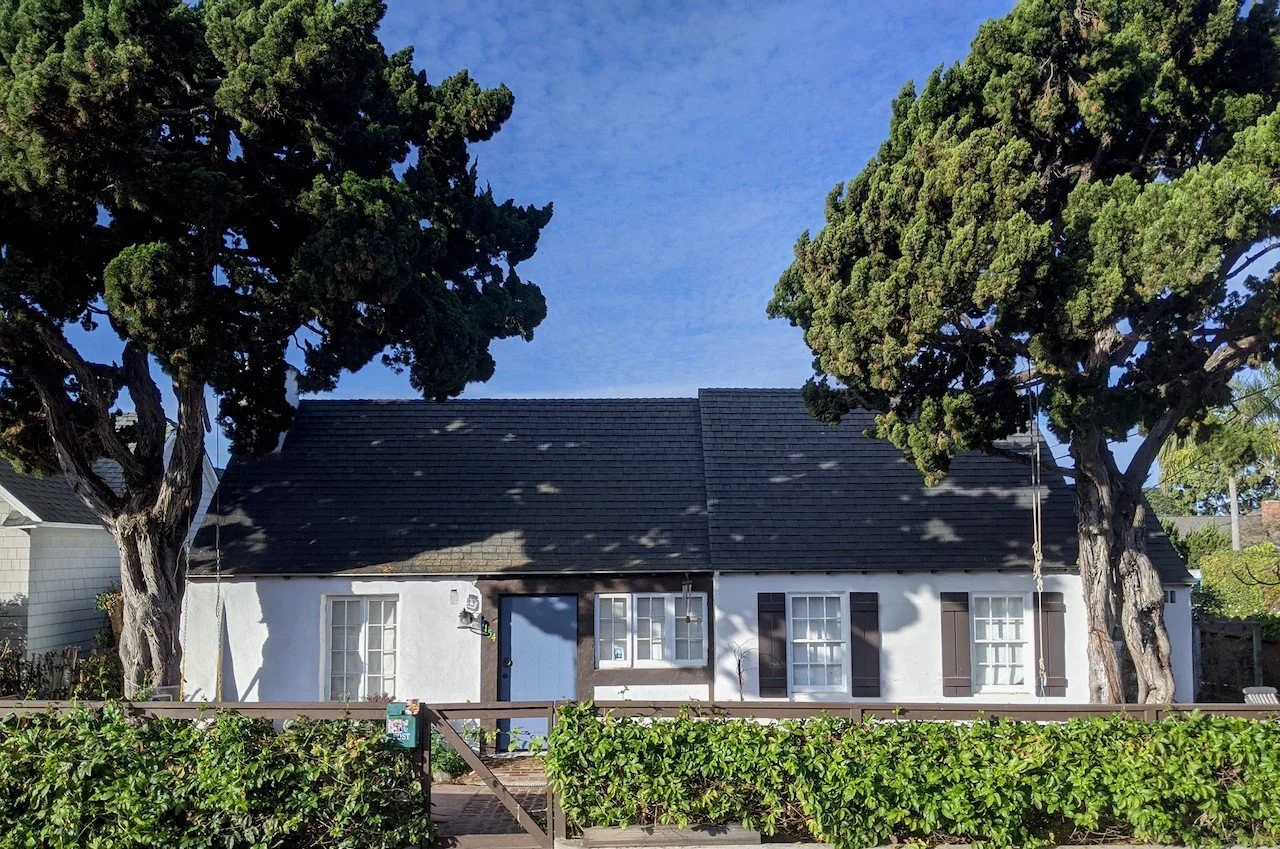 white house with shutters between 2 trees