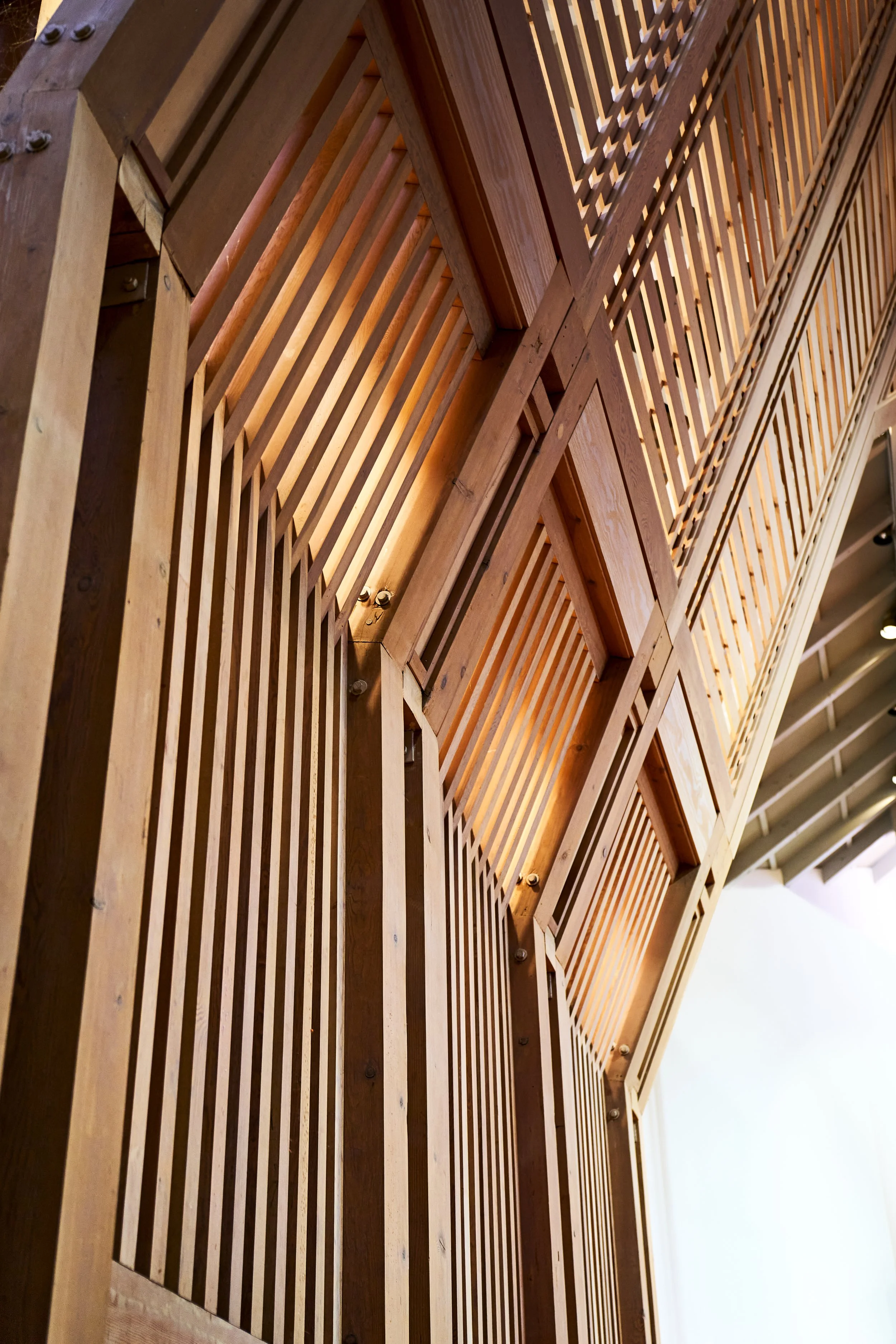 slightly angled slatted wood wall with light coming through the beams