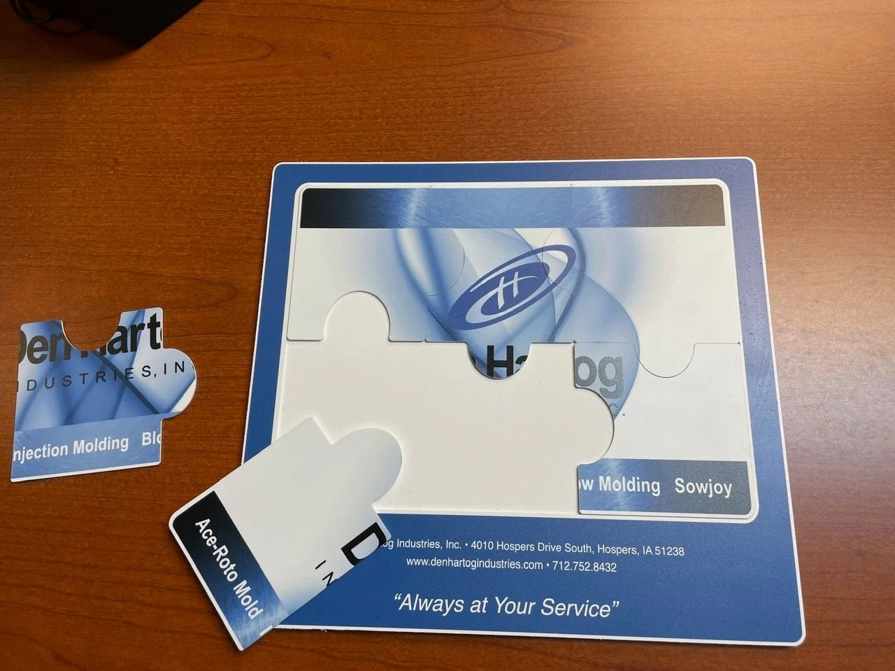Puzzle pieces with Benhart Industries branding on a wooden table.