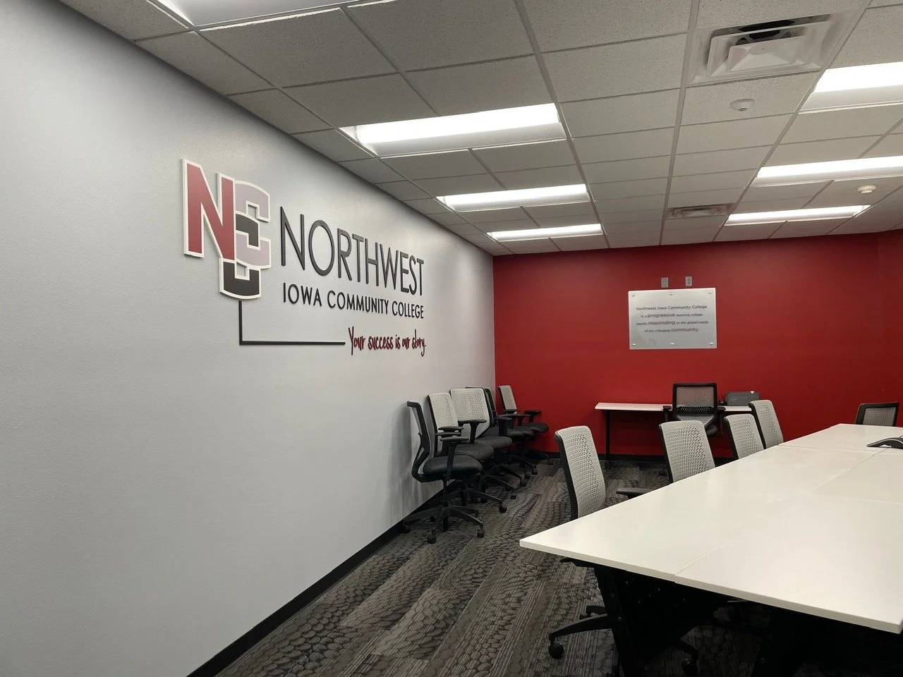 Conference room with chairs, tables, and a NW Iowa Community College sign on the wall.
