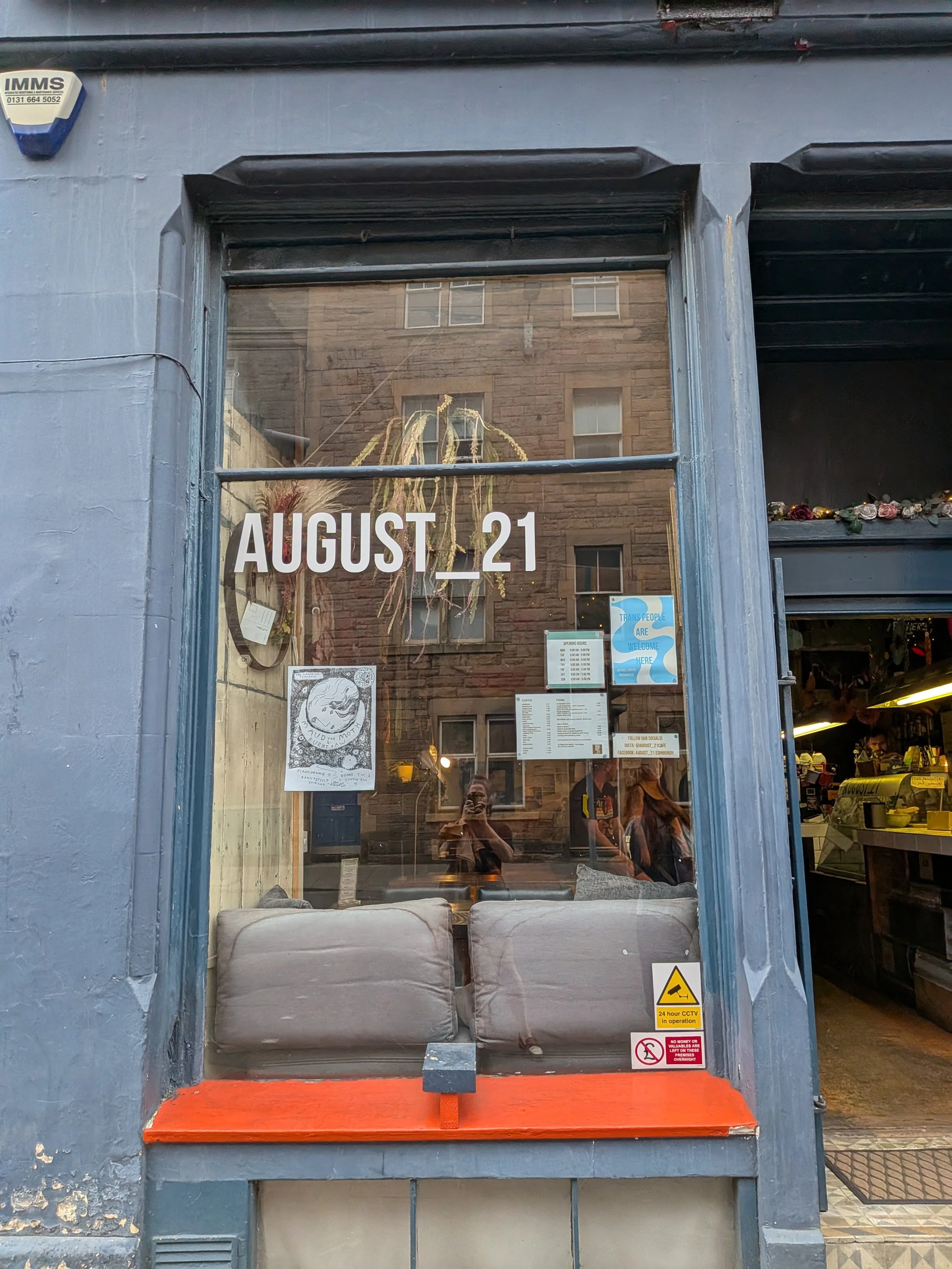 Large window with the words "August_21" on it and set into a dark blue-grey wall, with a window seat.