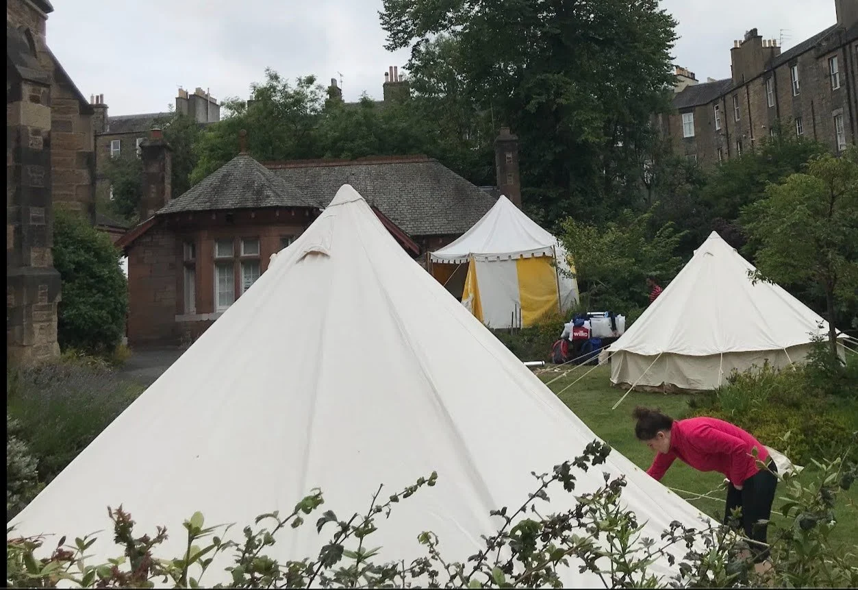 Three canvas tents surrounded by old stone buildings
