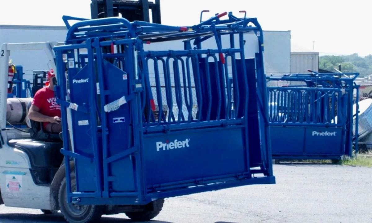 Blue chutes labeled 'Priefert' being moved by a forklift.