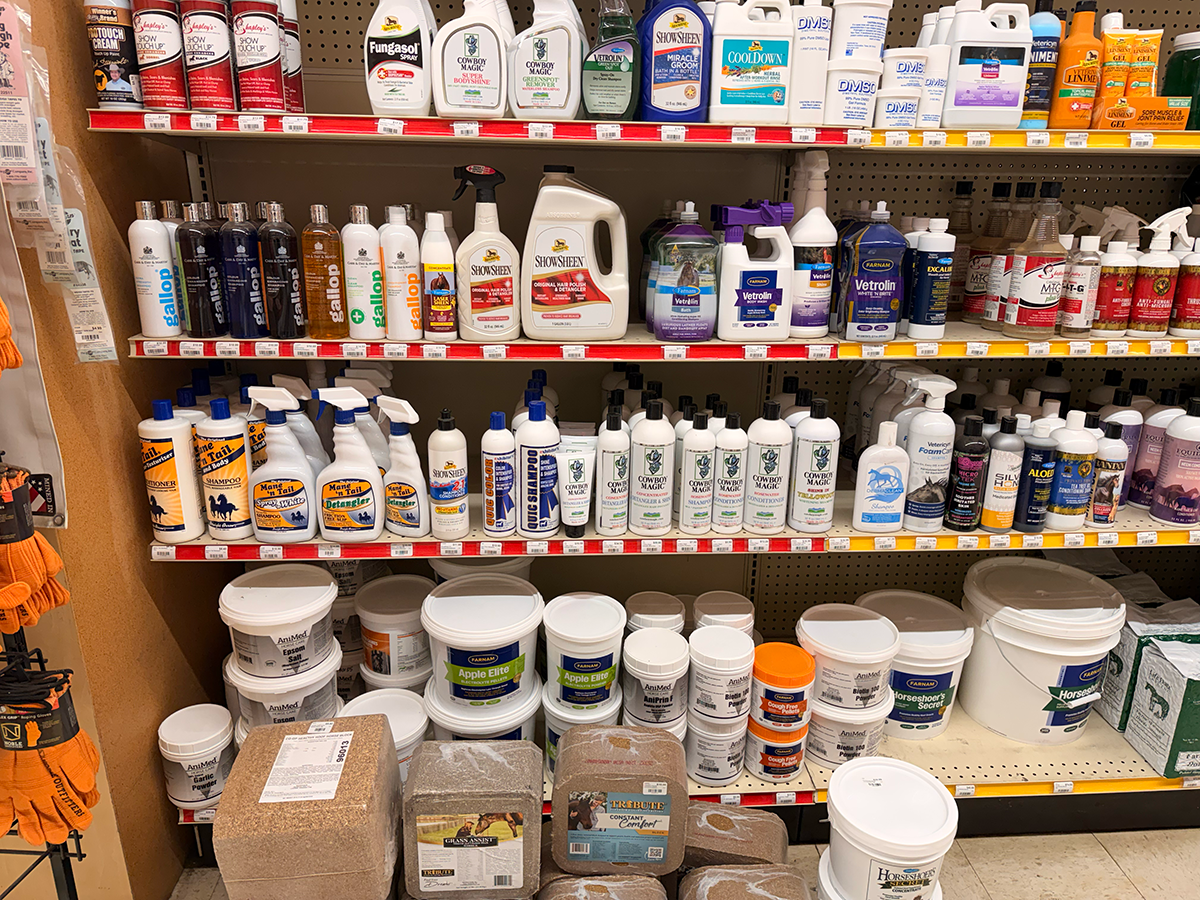 Shelf filled with various bottles and containers of animal care products, including grooming, wound spray, and supplements, in a pet store.