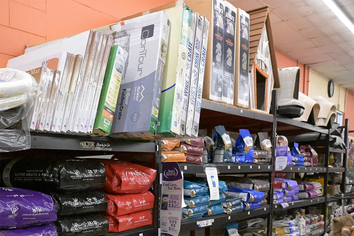Shelves stocked with various pet food bags, pet supplies, and boxed products in a store aisle.