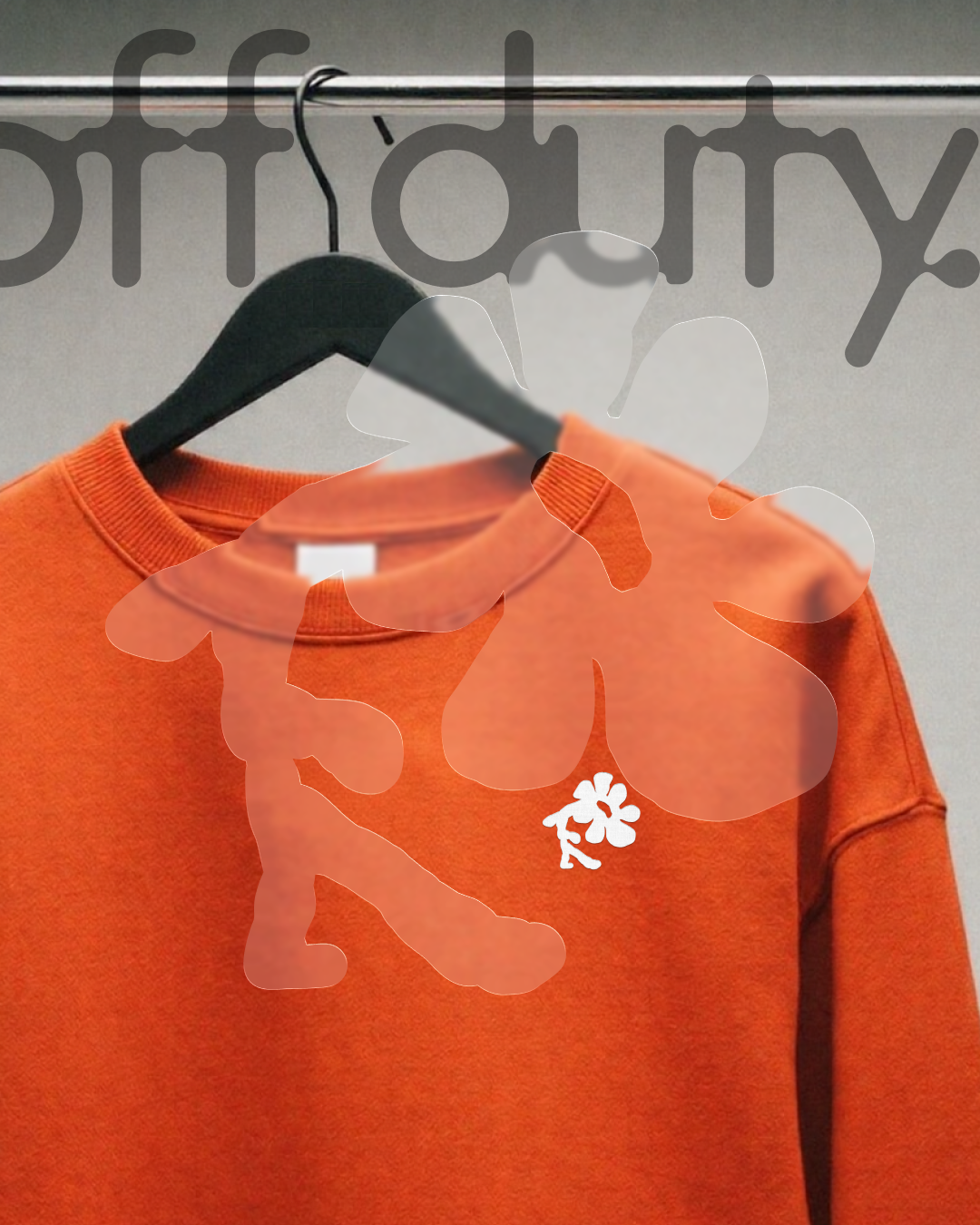 Pull orange avec un petit logo blanc représentant une fleur, accroché à un cintre en dessous d'une barre de vêtement.
