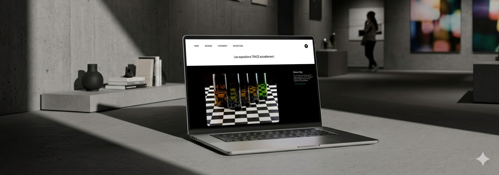 Un ordinateur portable ouvert affichant une page web sur un bureau dans un musée d'art. Le musée a des murs en béton et des œuvres d'art suspendues. Une personne se tient à l'arrière, observant une œuvre.