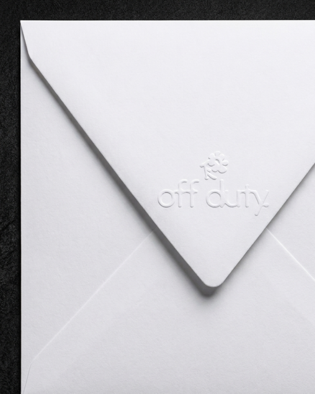 Une enveloppe blanche avec un rabat embossé portant le texte 'off duty' et une petite illustration de nuage de fumée.