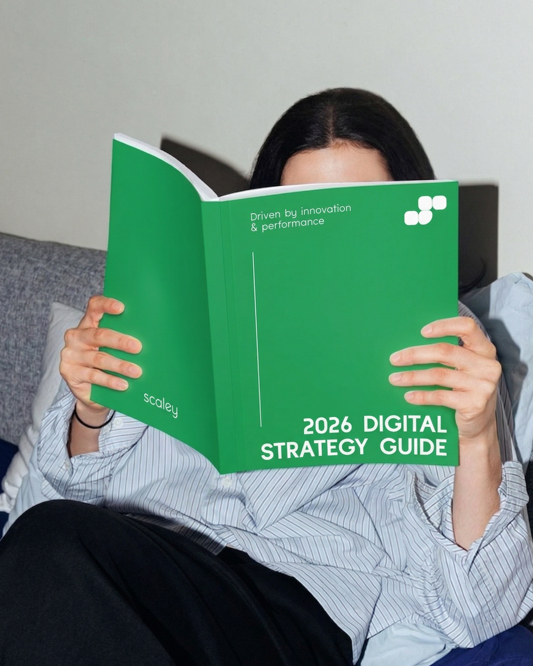 Personne lisant un guide sur la stratégie numérique de 2026, avec une couverture verte et le titre visible.