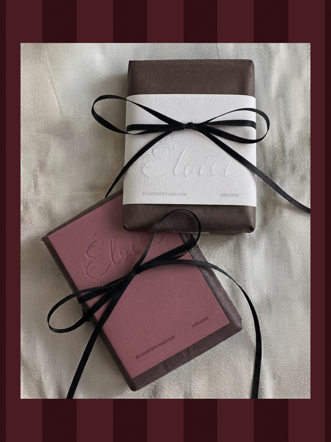 Photographie de deux paquets cadeaux enveloppés dans du papier brun foncé et noués d'un fin ruban noir en satin, présentés sur un fond texturé. Le paquet du haut est entouré d'une bande de papier blanc texturé avec le nom "Éloise" embossé et les insc