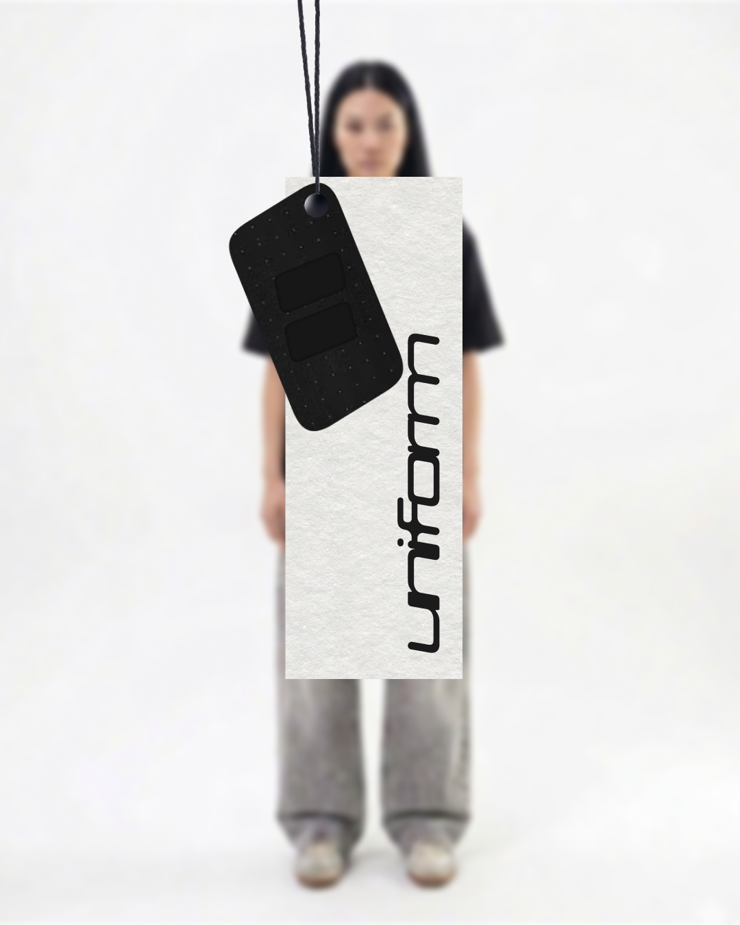 Une femme debout portant un grand panneau blanc avec le mot 'information' écrit verticalement. Un porte-clés noir avec deux compartiments est suspendu devant la caméra.