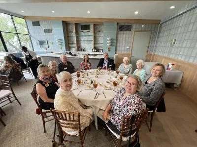 DRT members sitting around a dining table at the Artillery Club Galveston, smiling for the camera.