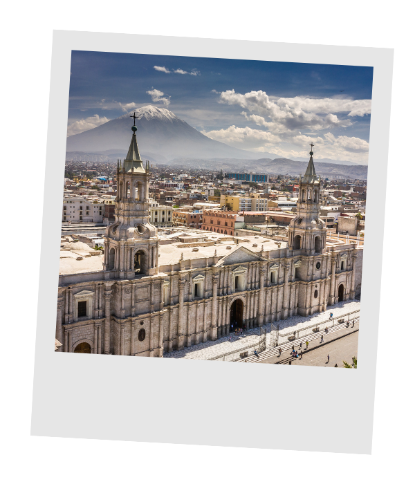 A historic church with twin bell towers in a city, with Mount Popocatépetl volcano in the background.