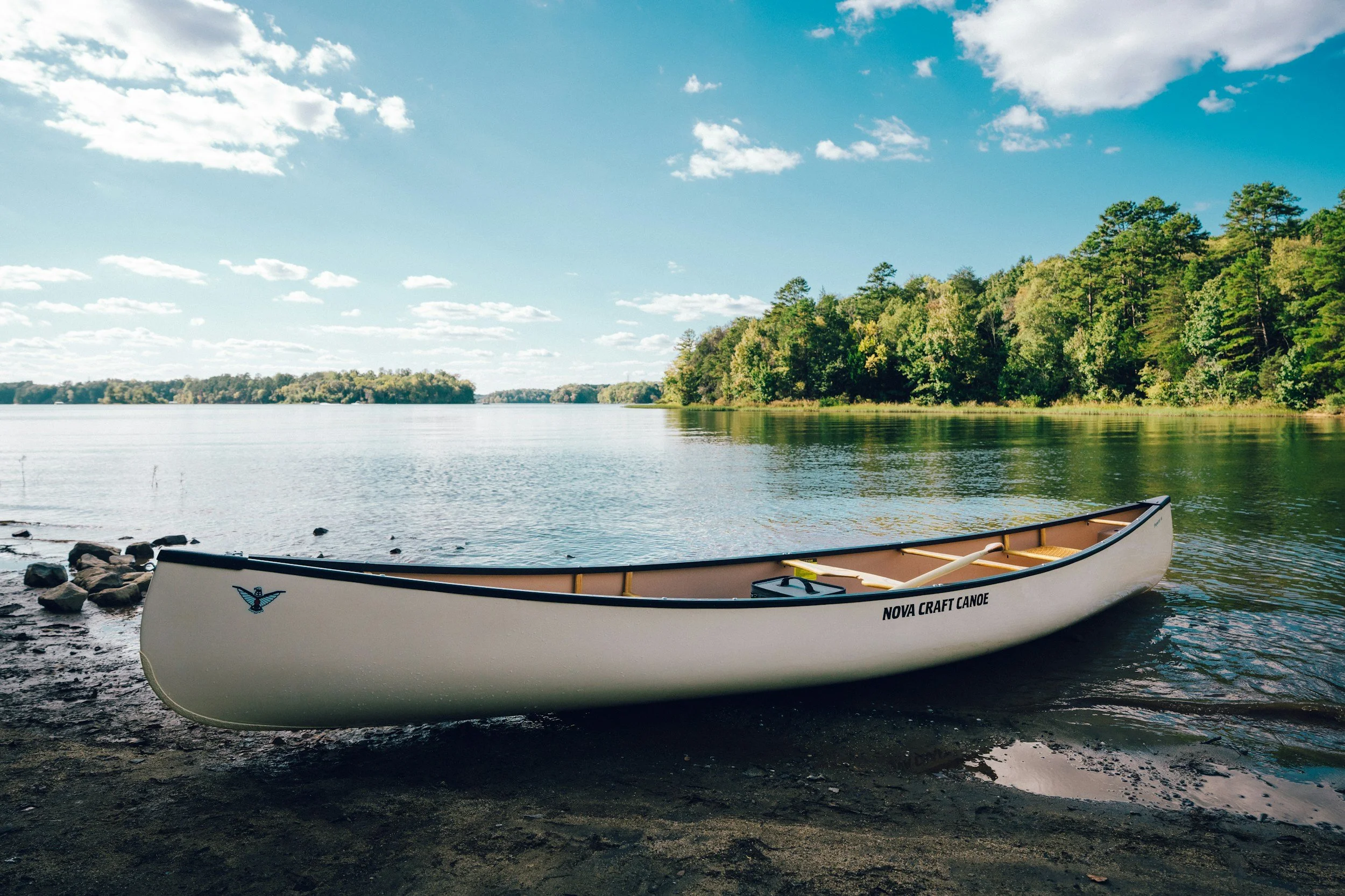 White canoe resting on a quiet lake surrounded by forest in Algonquin Provincial Park, Ontario