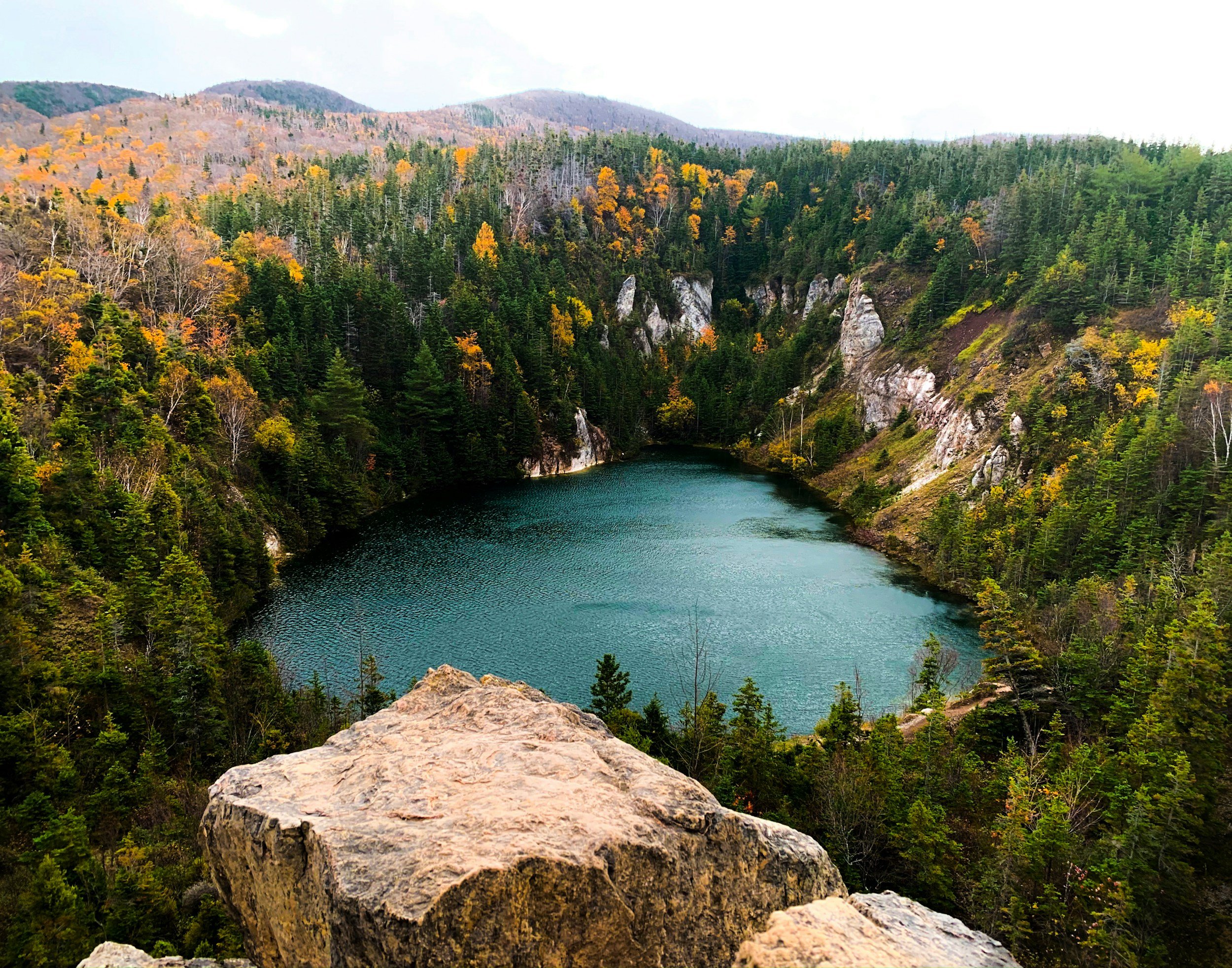 Autumn colors blanketing the hills above a lake along the Cabot Trail in Cape Breton, Nova Scotia
