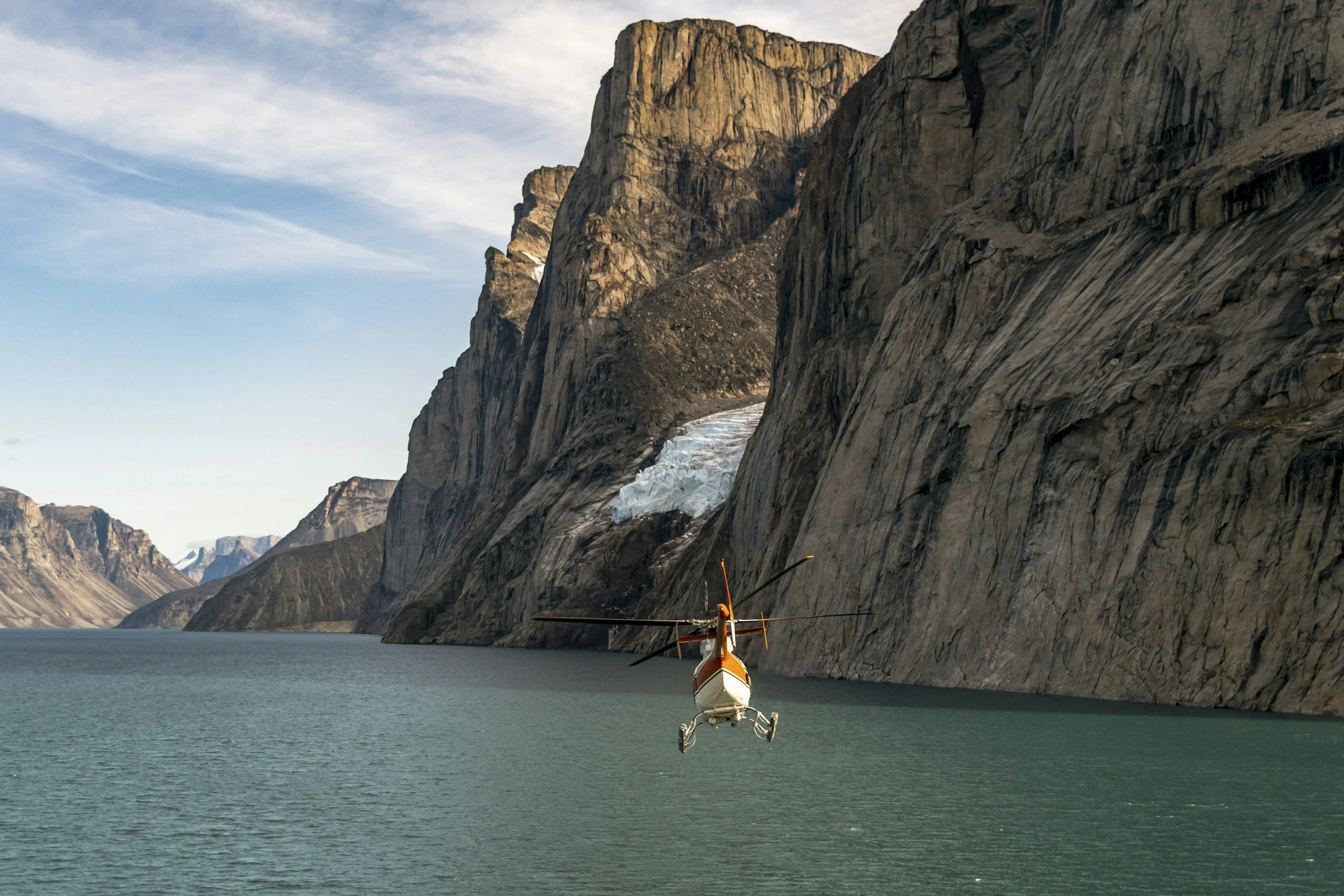 Helicopter flying near glacier-carved water and mountains in the Yukon