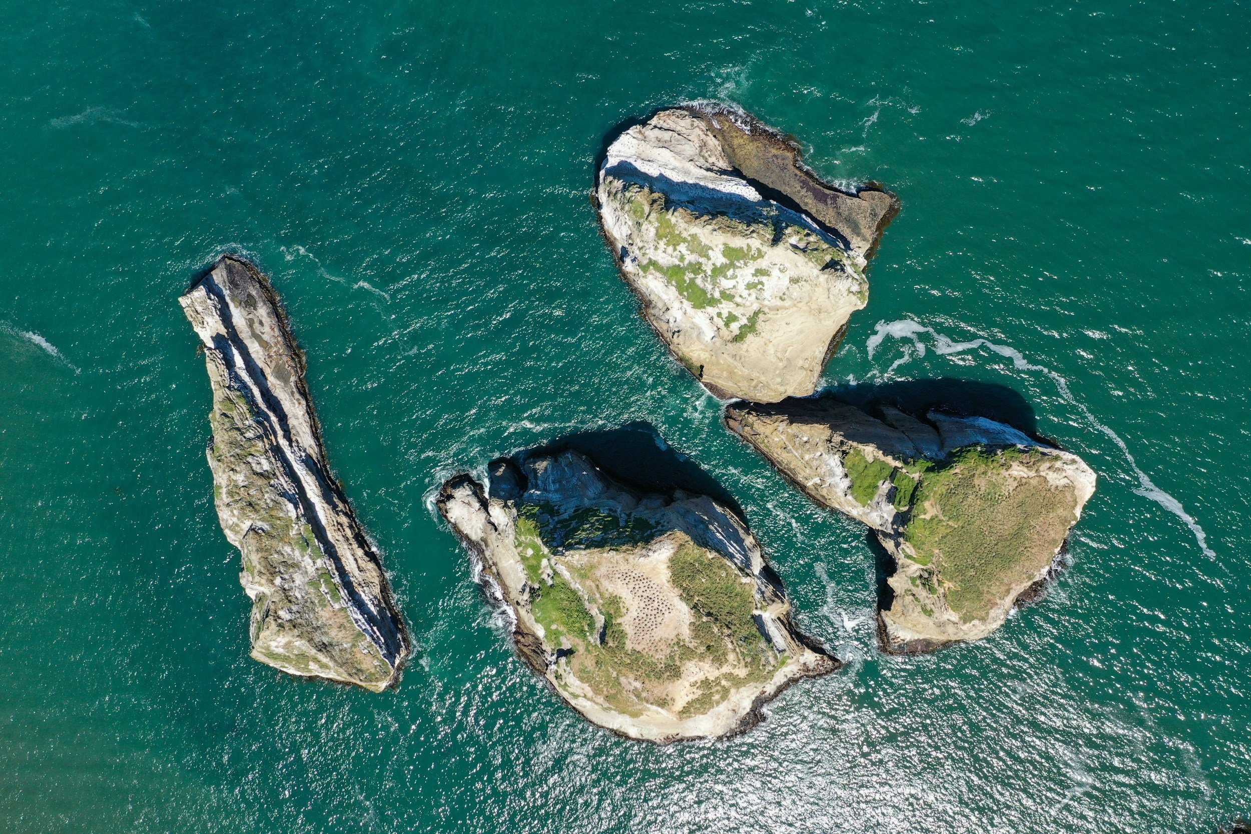 Aerial view of rugged rocky islets rising from deep green ocean waters off the coast of southern Chile.