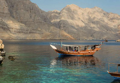 A boat floating on a calm body of water with mountains in the background.