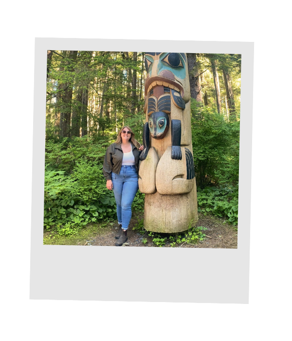 Travel advisor Piper Eskridge beside a carved totem pole in Alaska