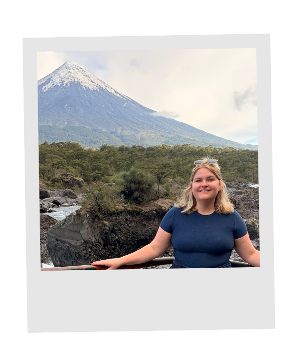 Piper smiling at an overlook beside rushing water, with the snowcapped Osorno Volcano rising behind her.