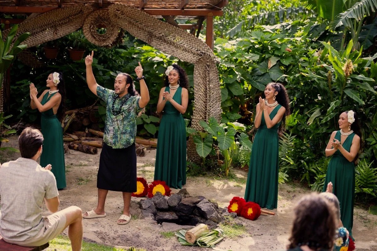 Performers in green dresses gathered around the imu at a traditional Hawaiian lū'au