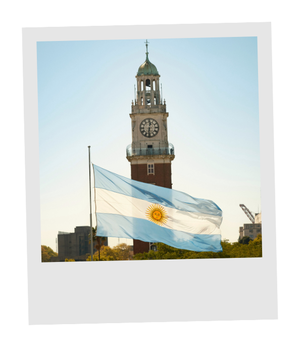 The Torre Monumental clock tower in Buenos Aires beside a waving Argentine flag.