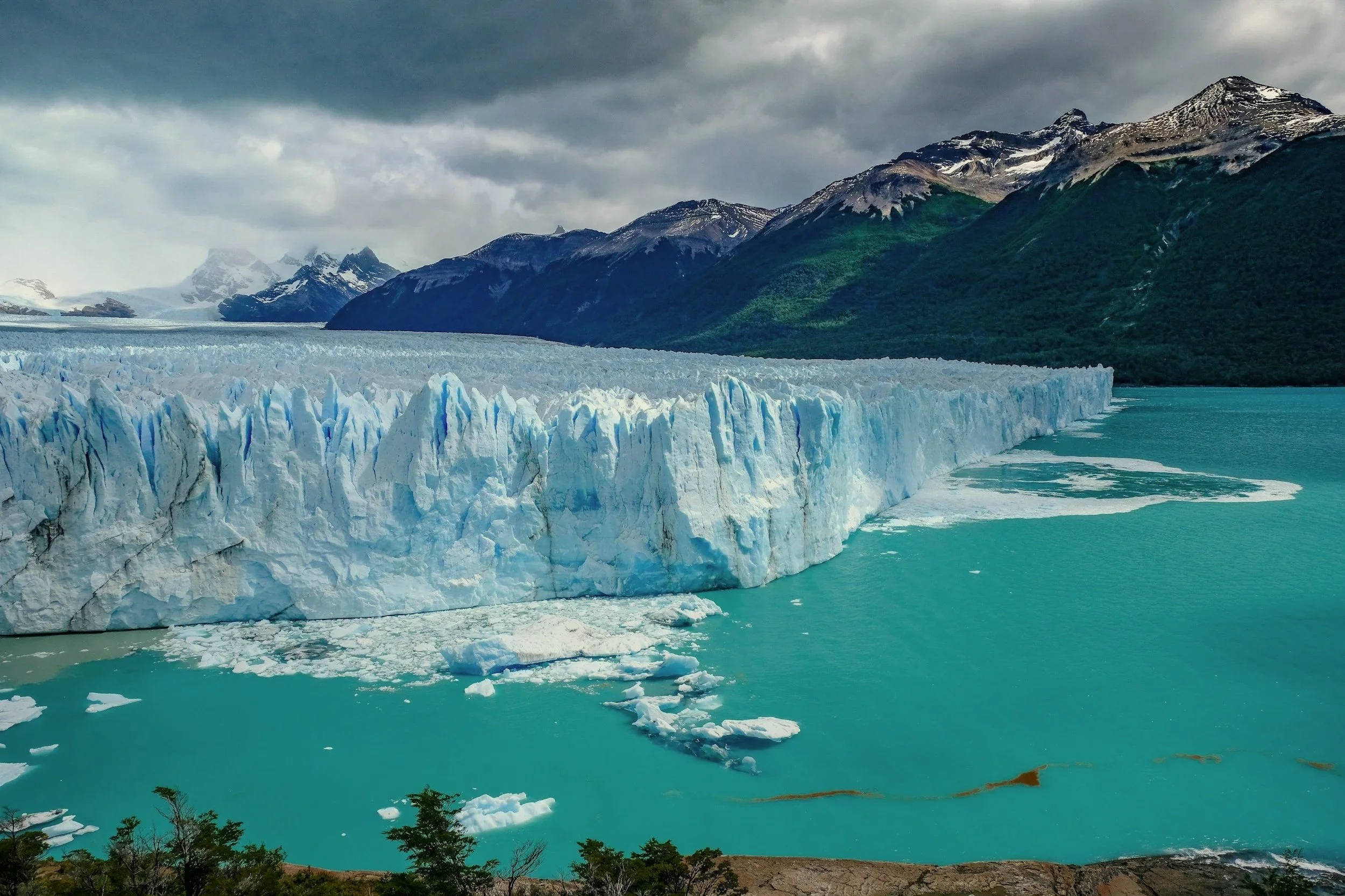 The towering blue and white ice wall of Perito Moreno Glacier meeting the turquoise waters of Lake Argentino in Patagonia.