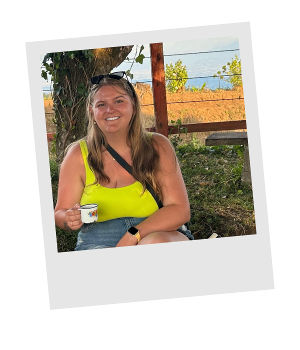 Piper Eskridge in a bright yellow shirt holding a cup of fresh coffee on a coffee farm near San José, Costa Rica