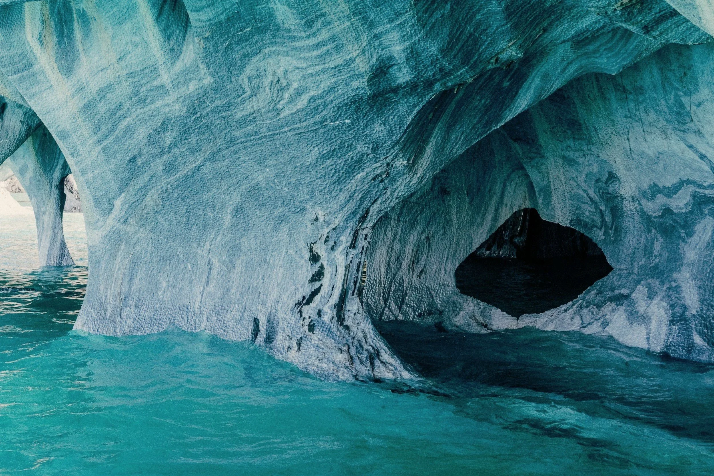 Swirling blue and white marble caverns curving over turquoise water on General Carrera Lake.