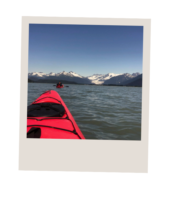 Red kayak paddling through calm waters near Juneau, Alaska