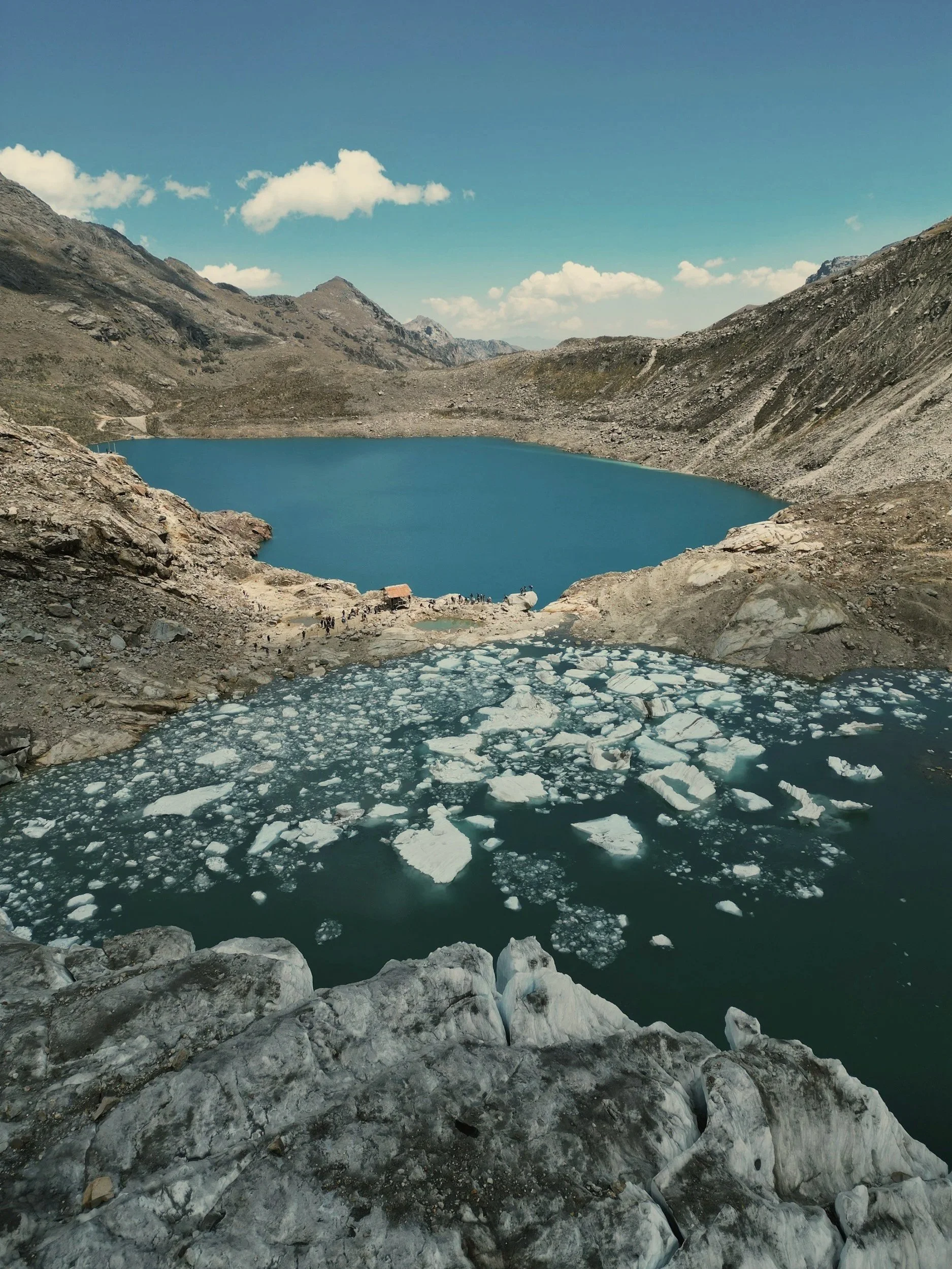 A turquoise glacial lake surrounded by rocky mountain slopes in Peru's Cordillera Blanca.