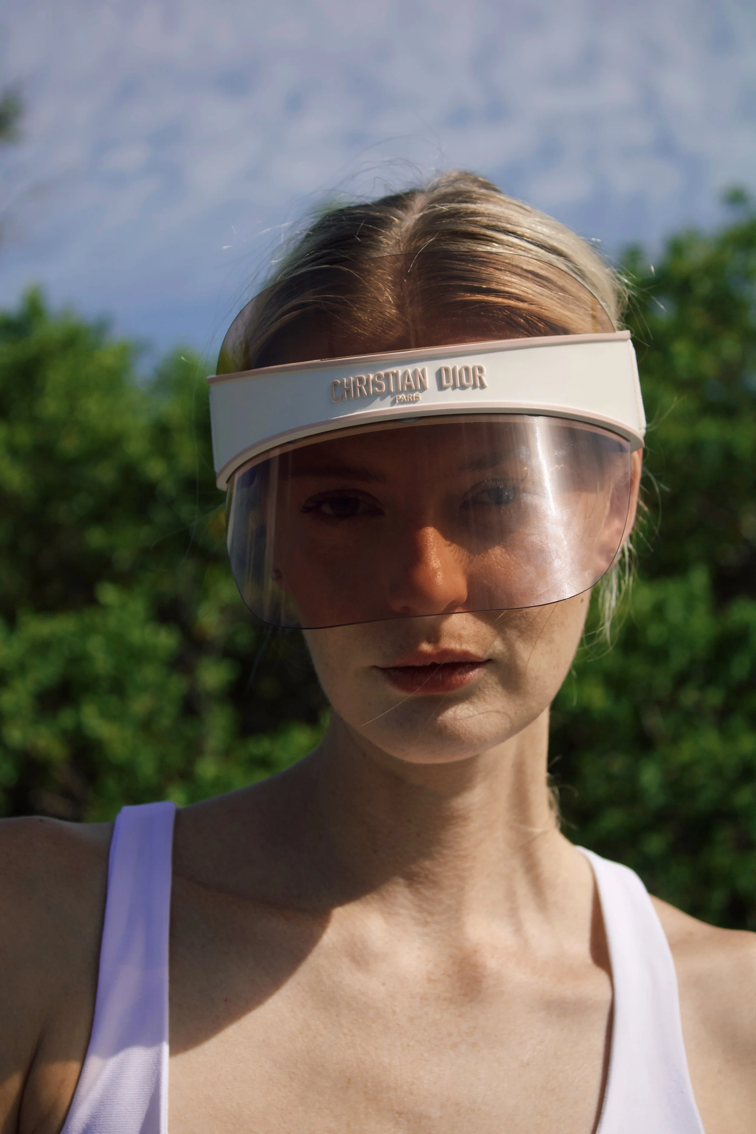 a close up photo of a model wearing a pink and white dior visor