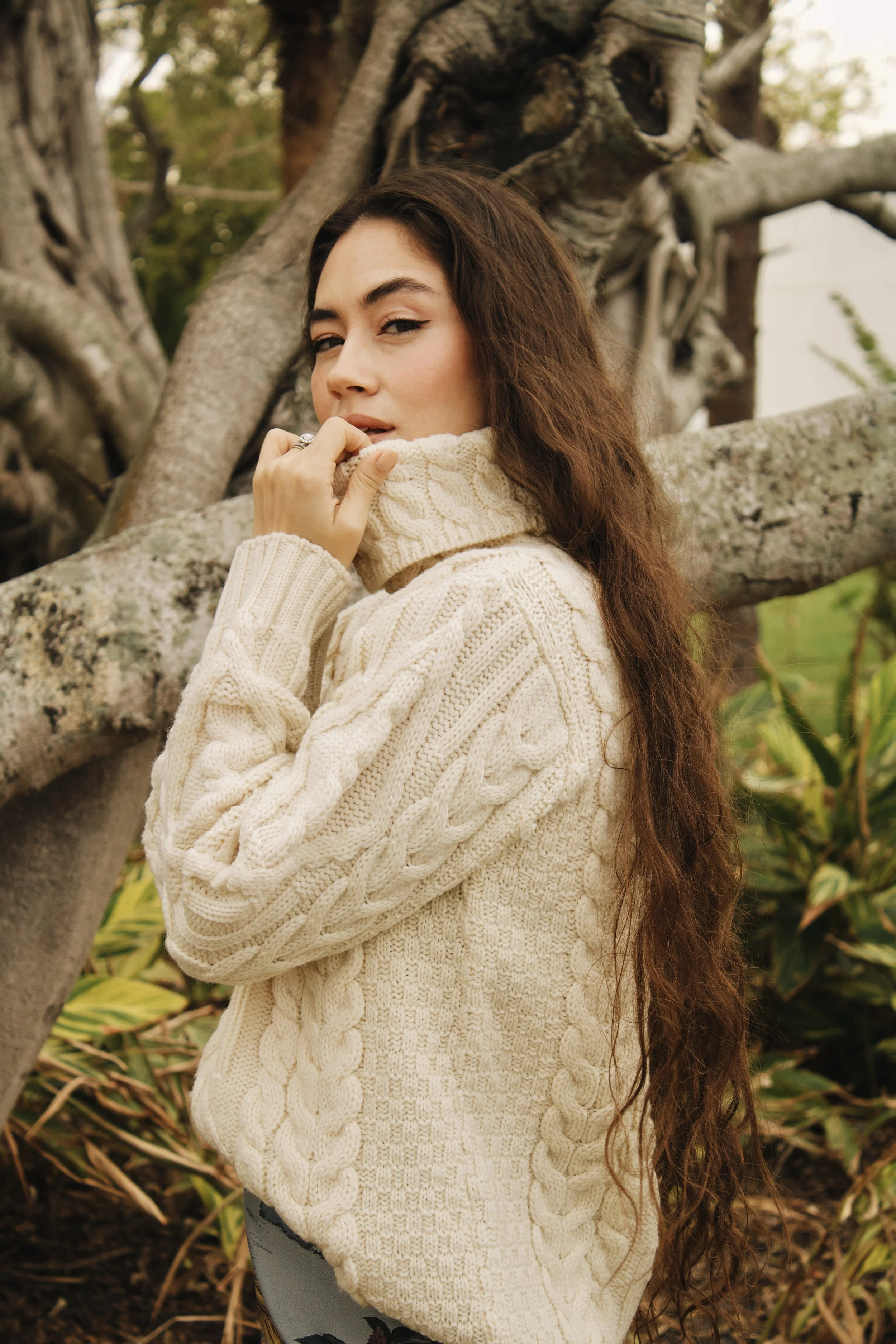 model in the forest wearing a cable knit sweater and chanel bag