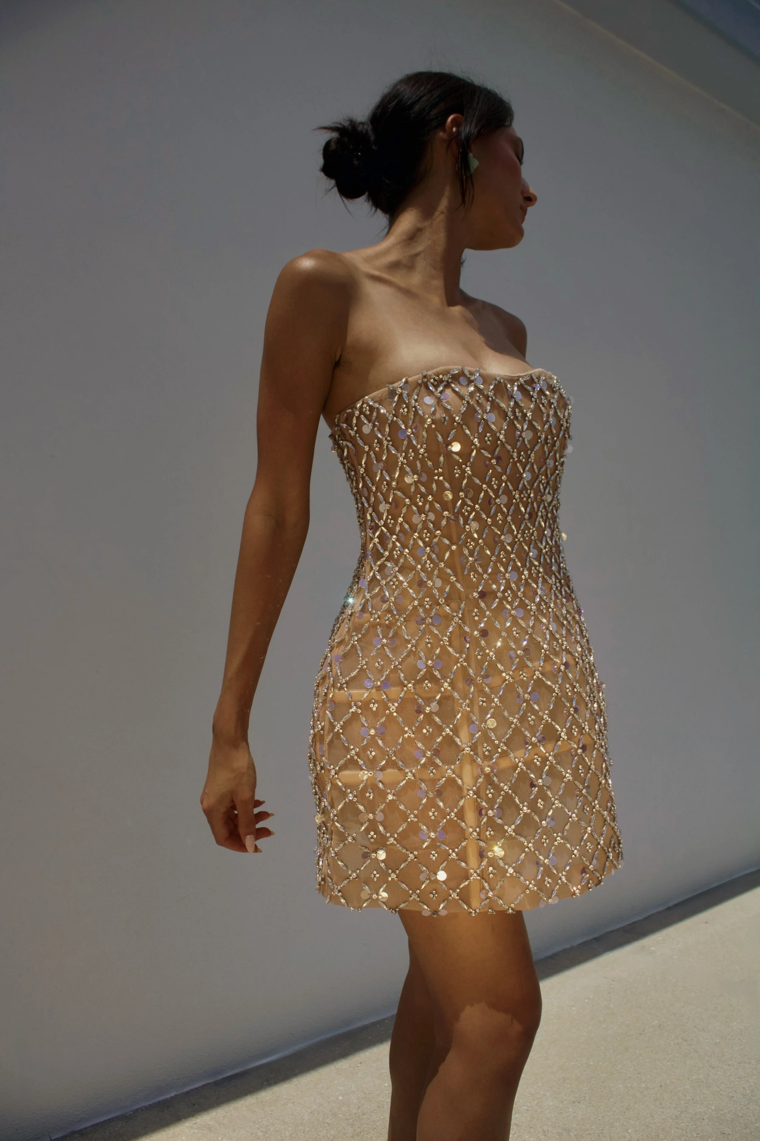 a model stands in golden light while wearing a sequin mini dress and gucci teal heels