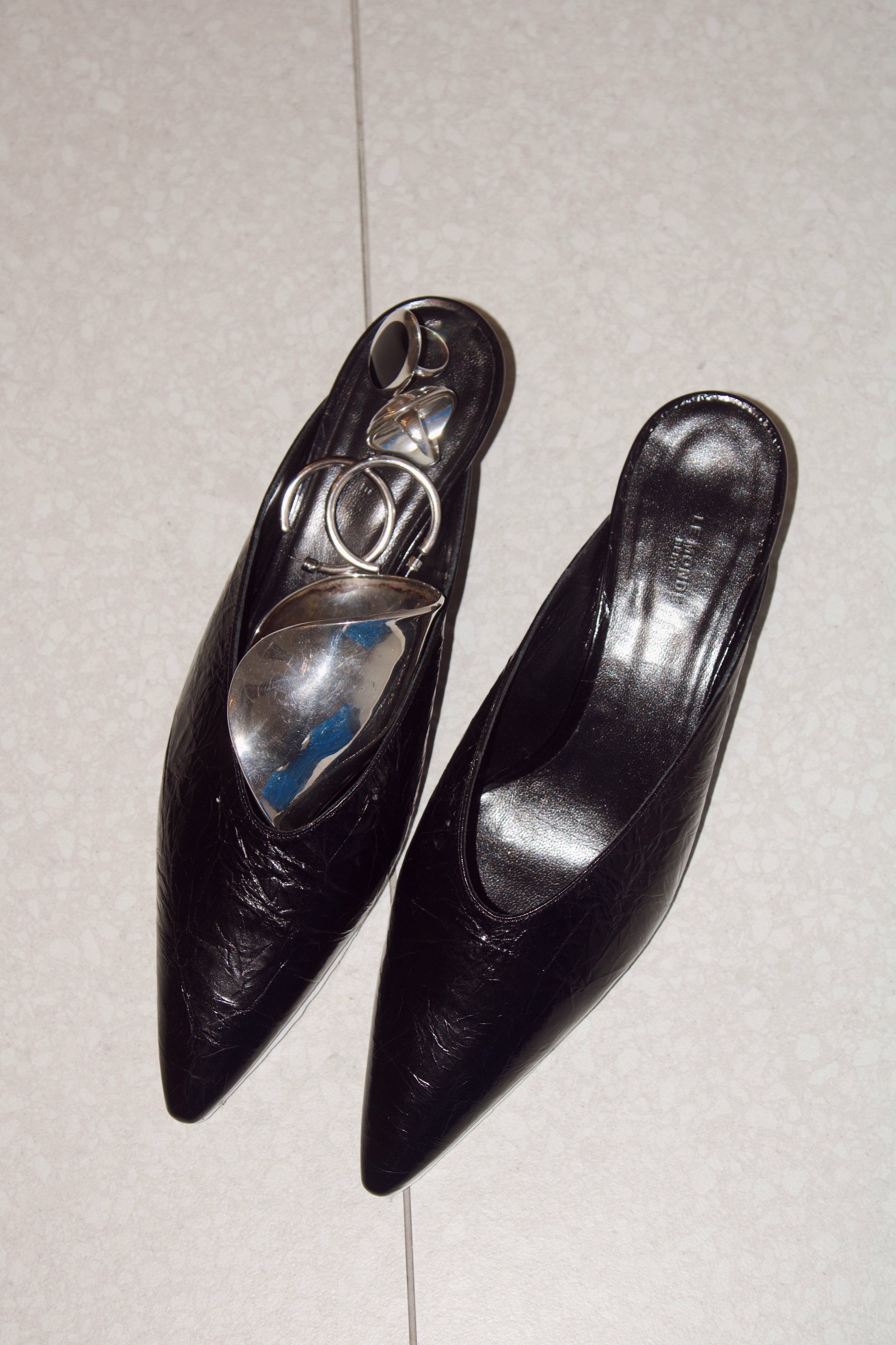 a flash photo of leather heels with sterling silver jewelry resting in the insoles