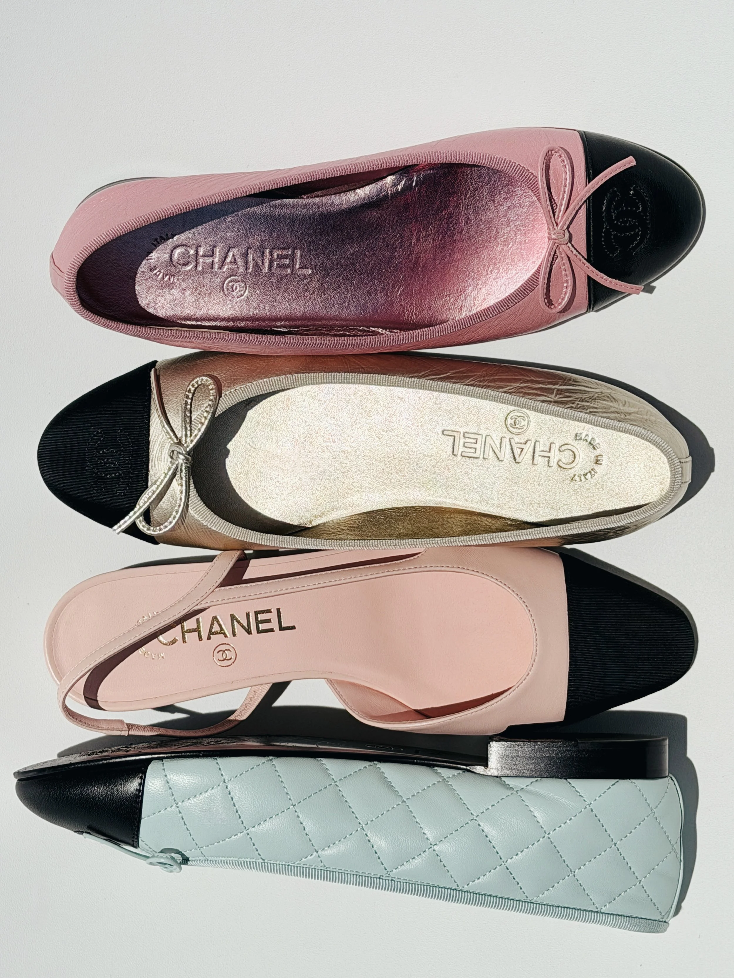 a flat flay photograph of four chanel ballet flats in the sun