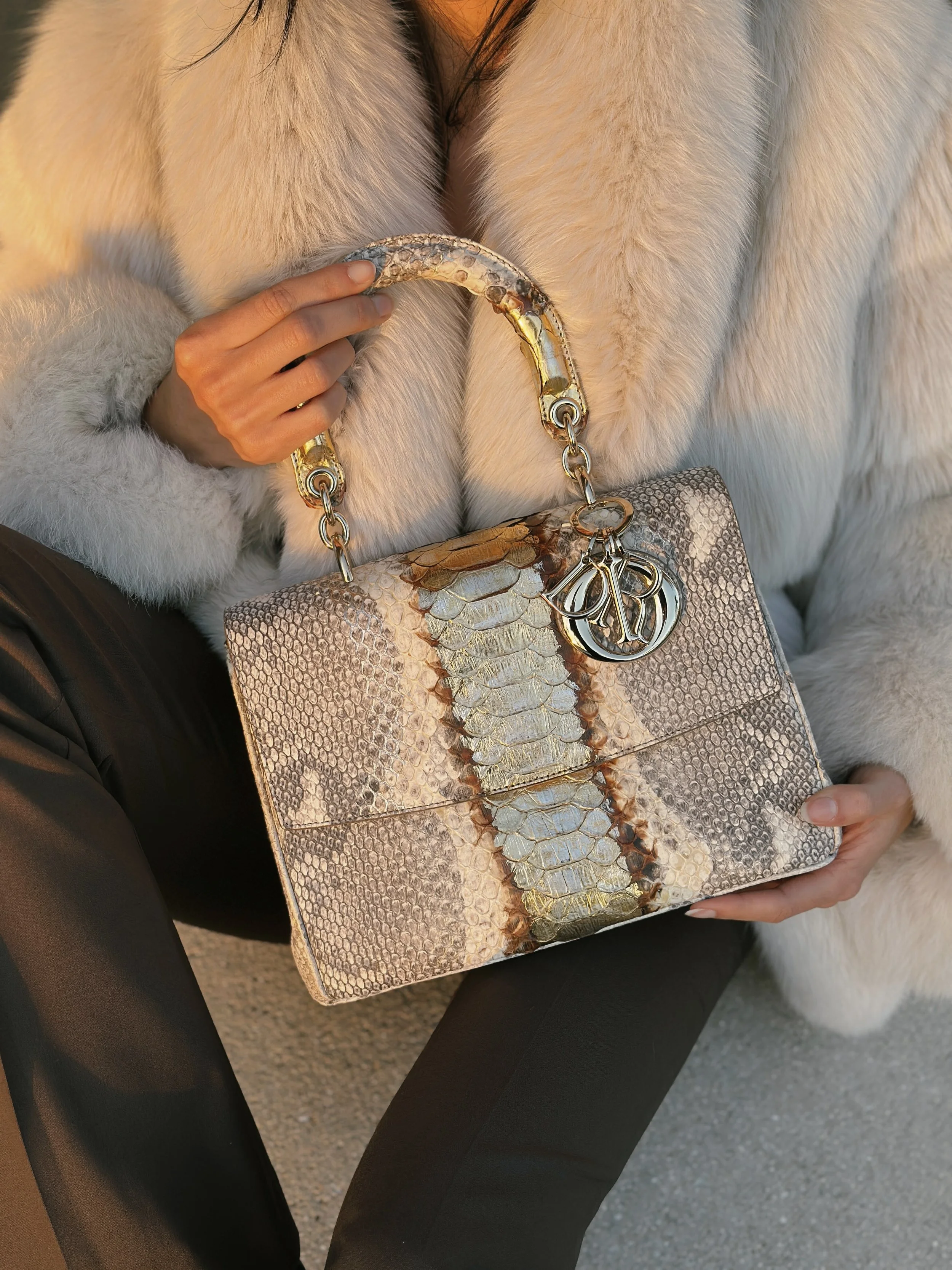 a model in a vintage fur coat holds a dior python Lady Dior bag