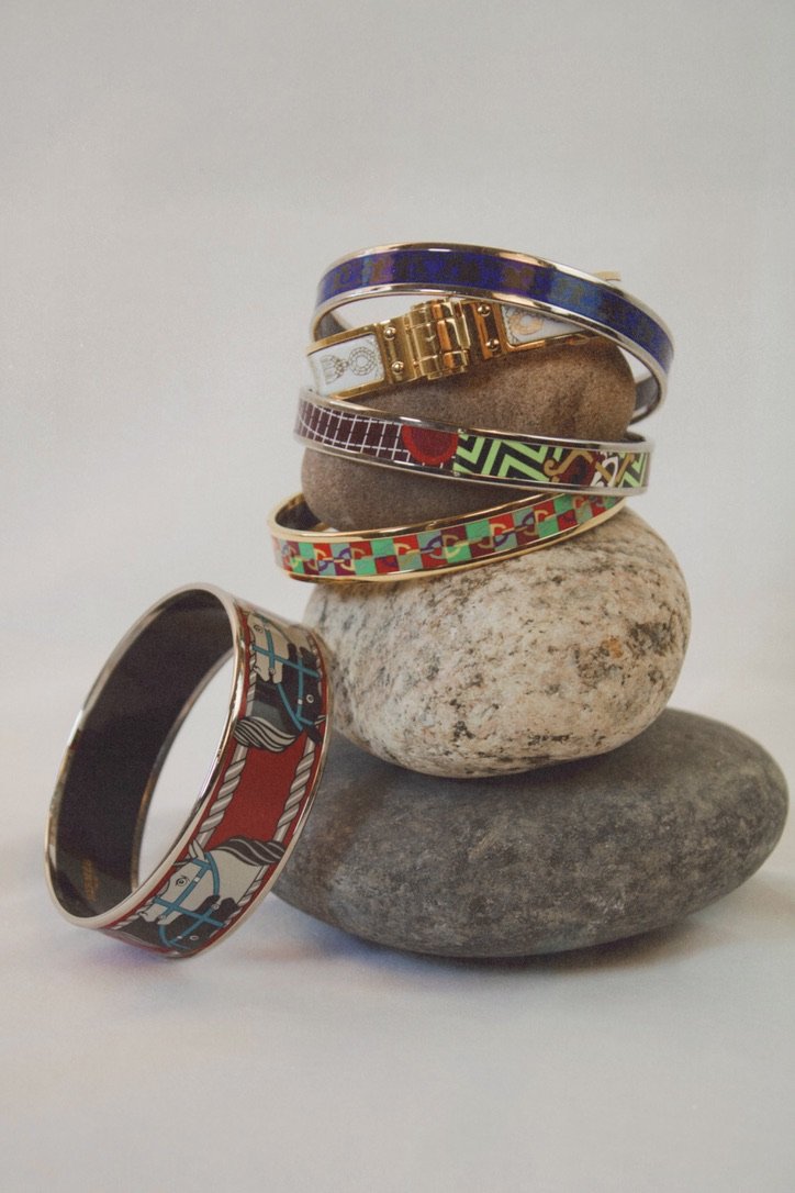 studio photoshoot of hermes bracelets stacked on top of stones