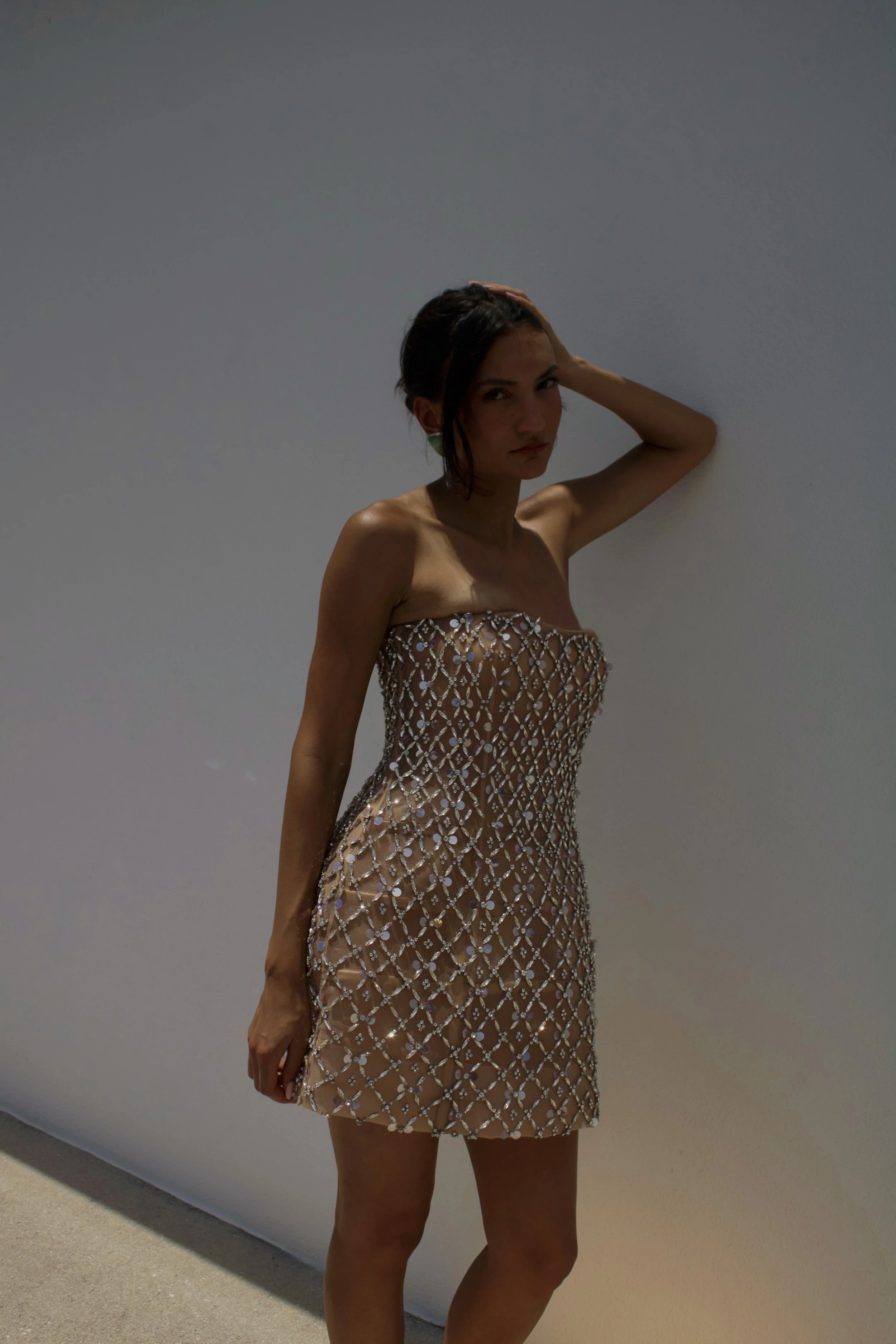 a model stands in golden light while wearing a sequin mini dress and gucci teal heels