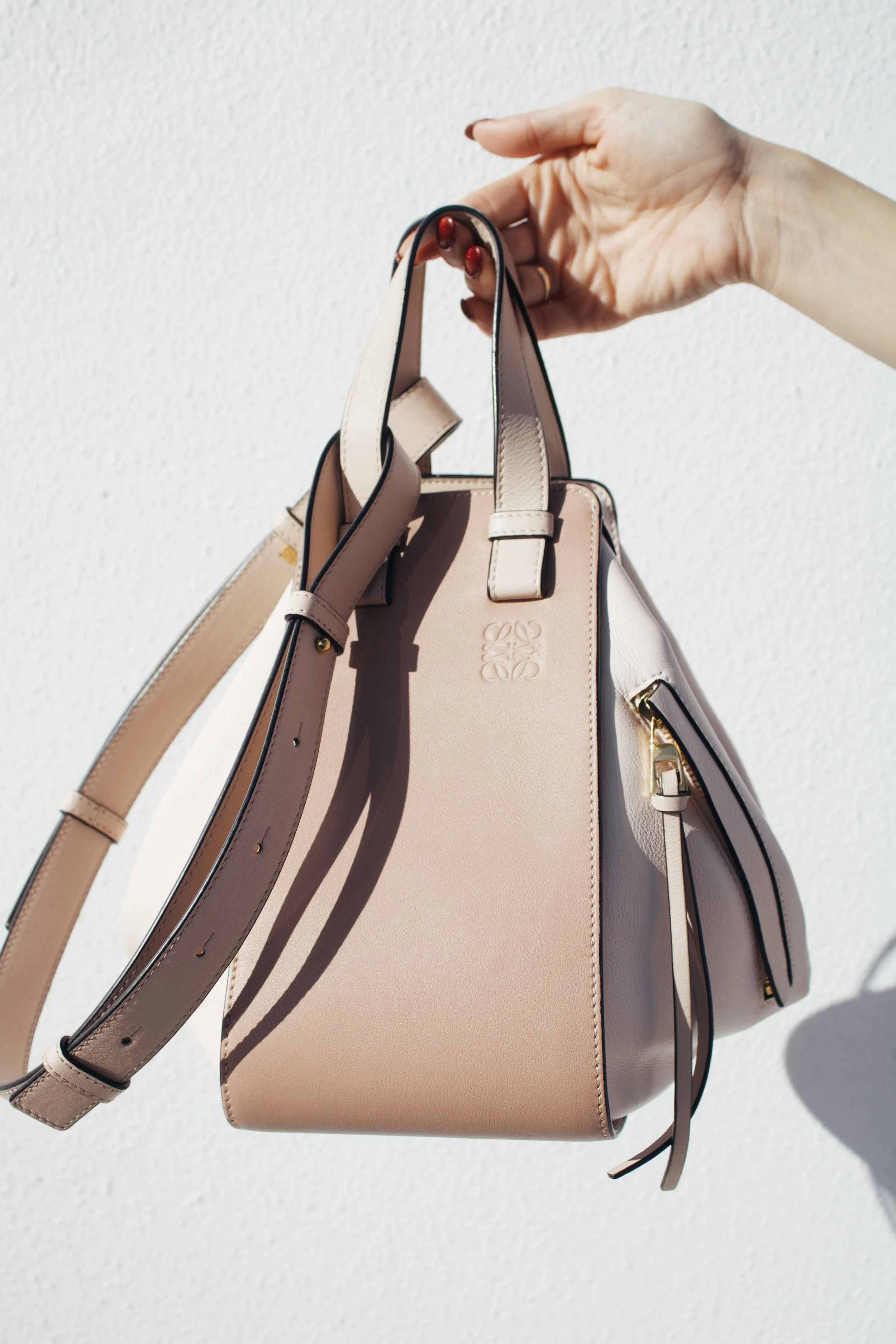 a hand holds out a light pink loewe hammock bag