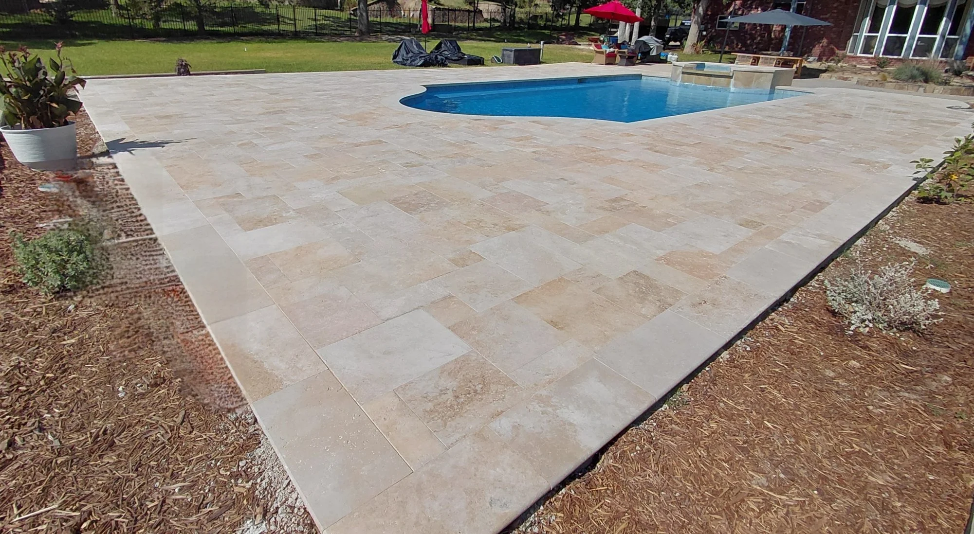 Large backyard pool deck of natrual travertine stone with 360 degree coping.