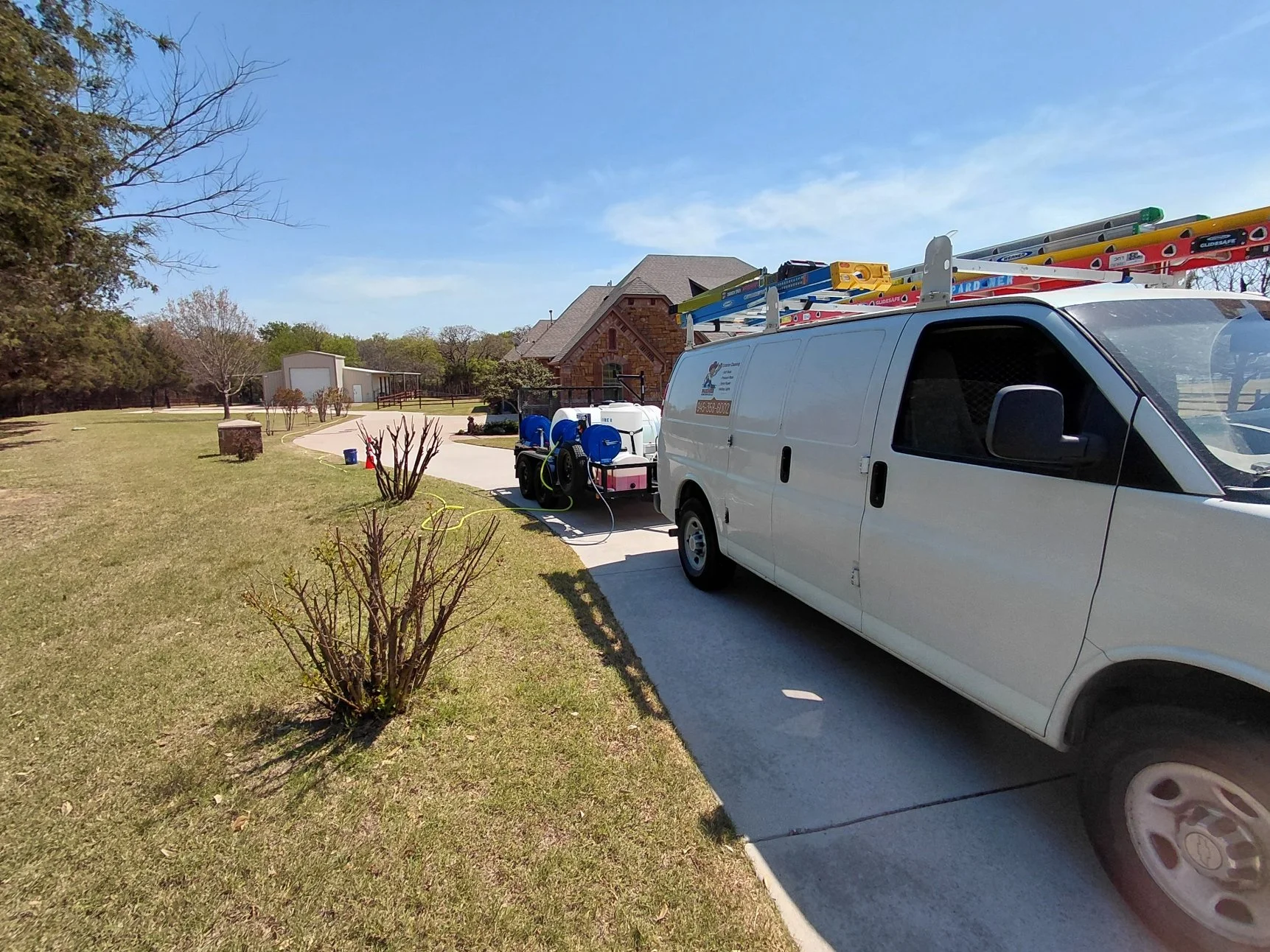 Pressure and Soft washing trailer and work van on the job at extremely long rural driveway