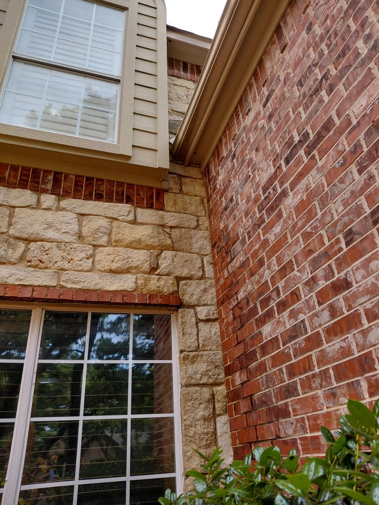 Detailed view of algae removal without pressure on a house with soft stone next to brick.