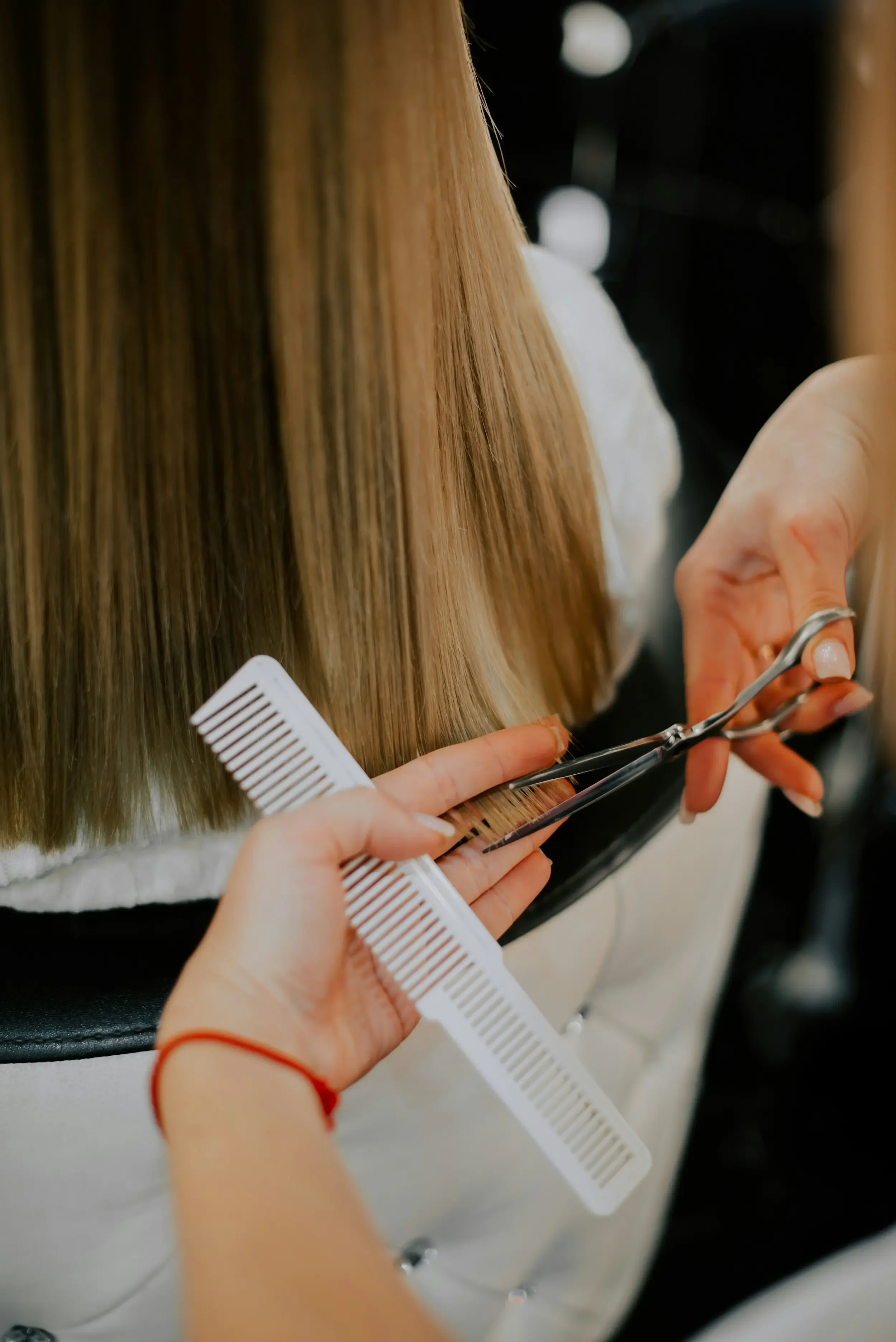 Stylist cutting long blonde hair with scissors and comb — haircut services at Itsa Salon in Puyallup, WA