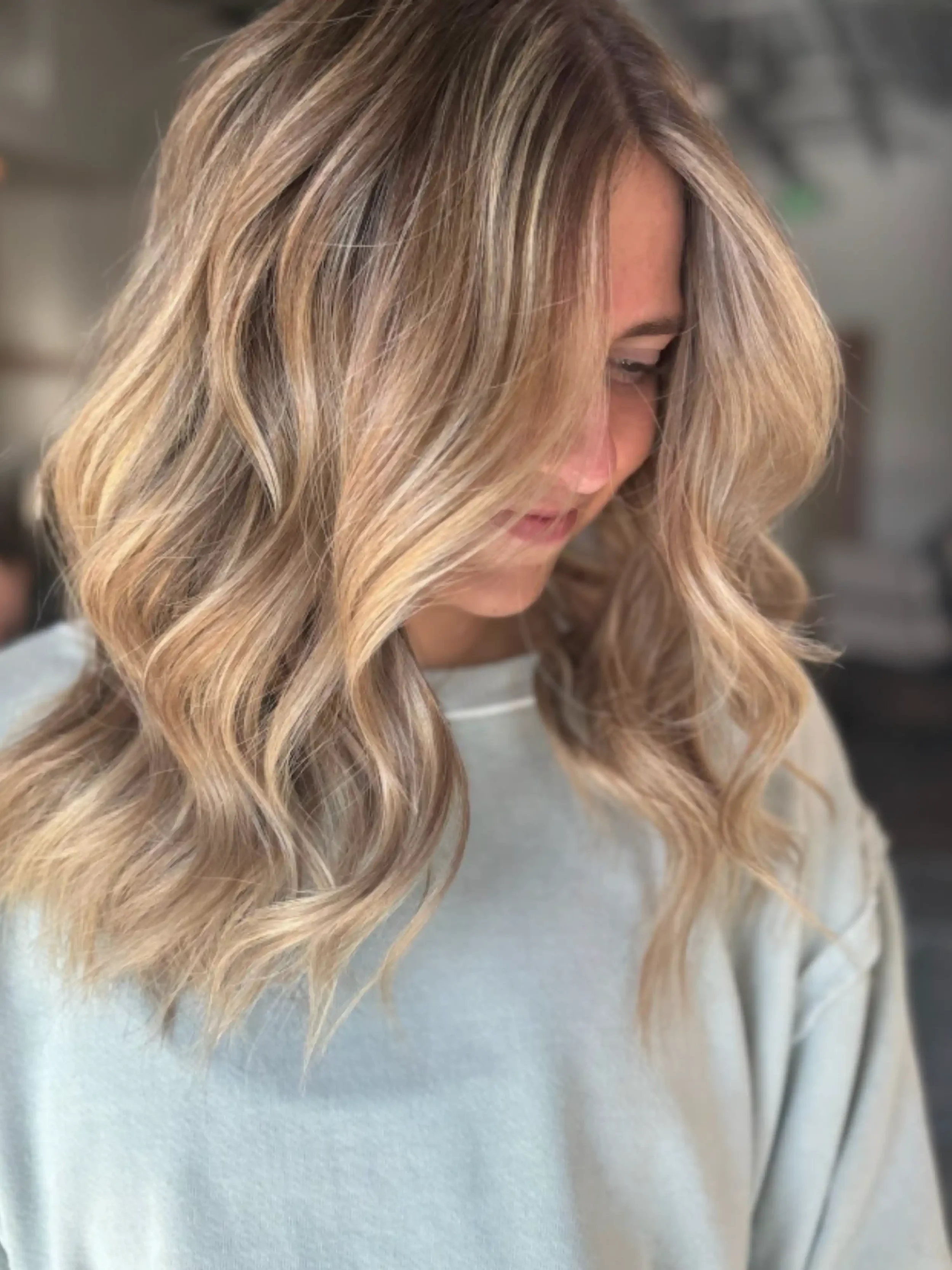 Soft lived-in blonde with sun-kissed highlights, side profile — dimensional color at Itsa Salon in Puyallup, WA